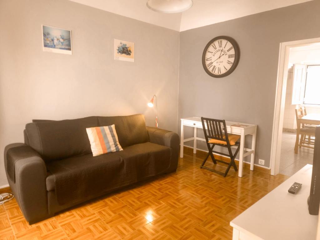 a living room with a couch and a clock on the wall at Casa do Mestre By Gt House in Évora