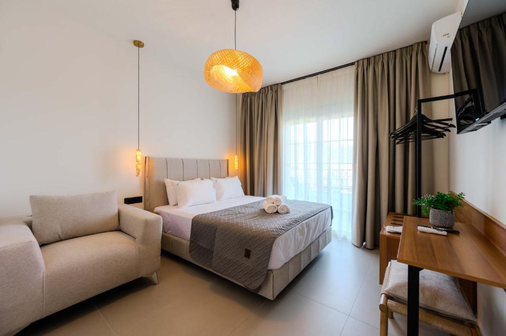 a bedroom with a bed and a chair and a couch at Blue Bay Hotel in Skala Potamias