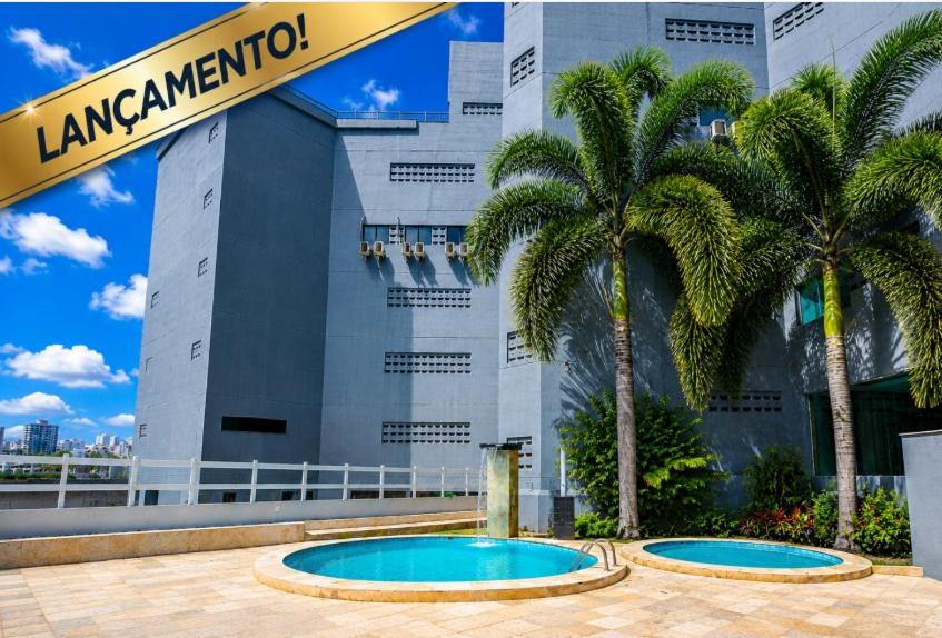 a hotel with palm trees in front of a building at Atlas Beach Hotel in Fortaleza