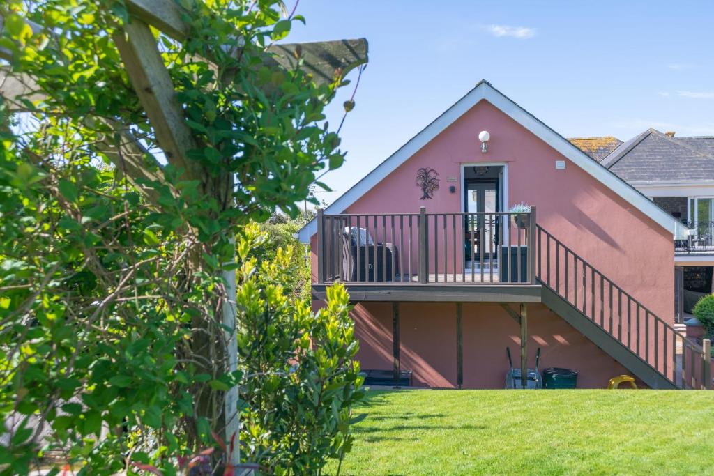 a pink house with a balcony and a yard at Garden View Apartment in Salcombe