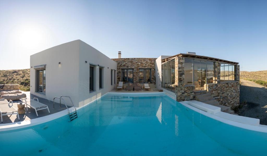 a house with a large swimming pool next to a building at Villa Cycladic View Syros in Azolimnos Syros