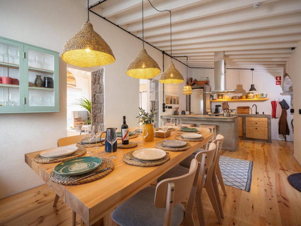 a dining room with a wooden table with chairs at GuestReady - ALMA - Island House in Faial da Terra