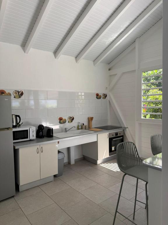 a white kitchen with a sink and a refrigerator at Tropical Lodge in Petit-Bourg
