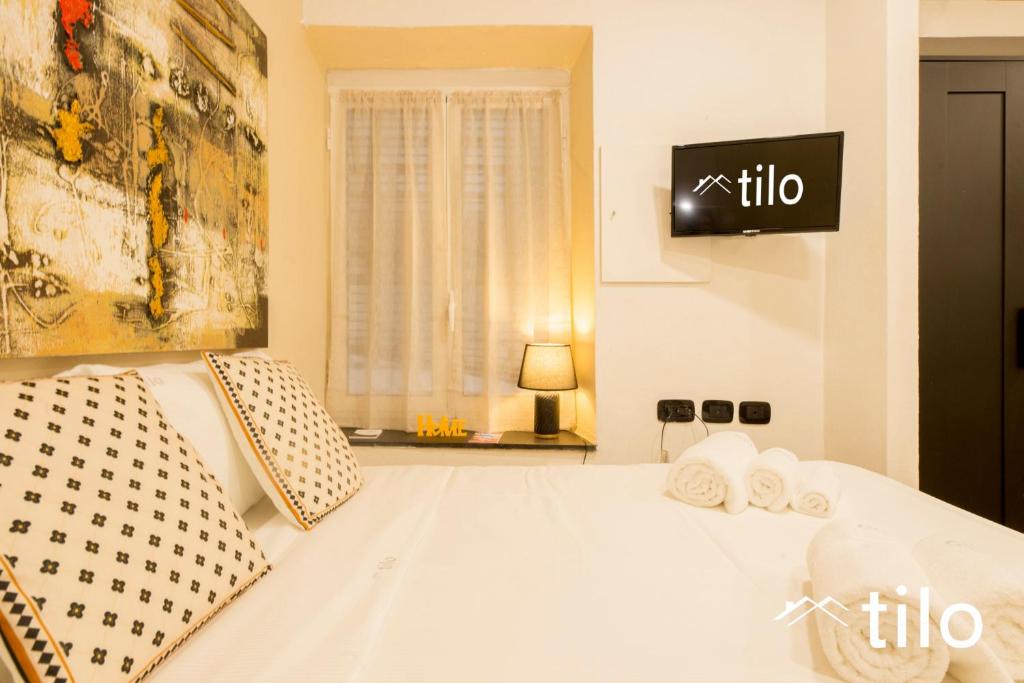 a bedroom with a white bed with a tv on the wall at City center 4’|Studio|wifi|By tilo in Genoa