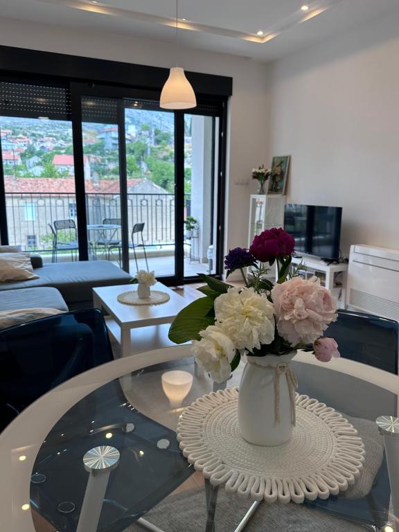 un vaso di fiori su un tavolino di vetro in soggiorno di Apartman Mango & Mia a Trebinje