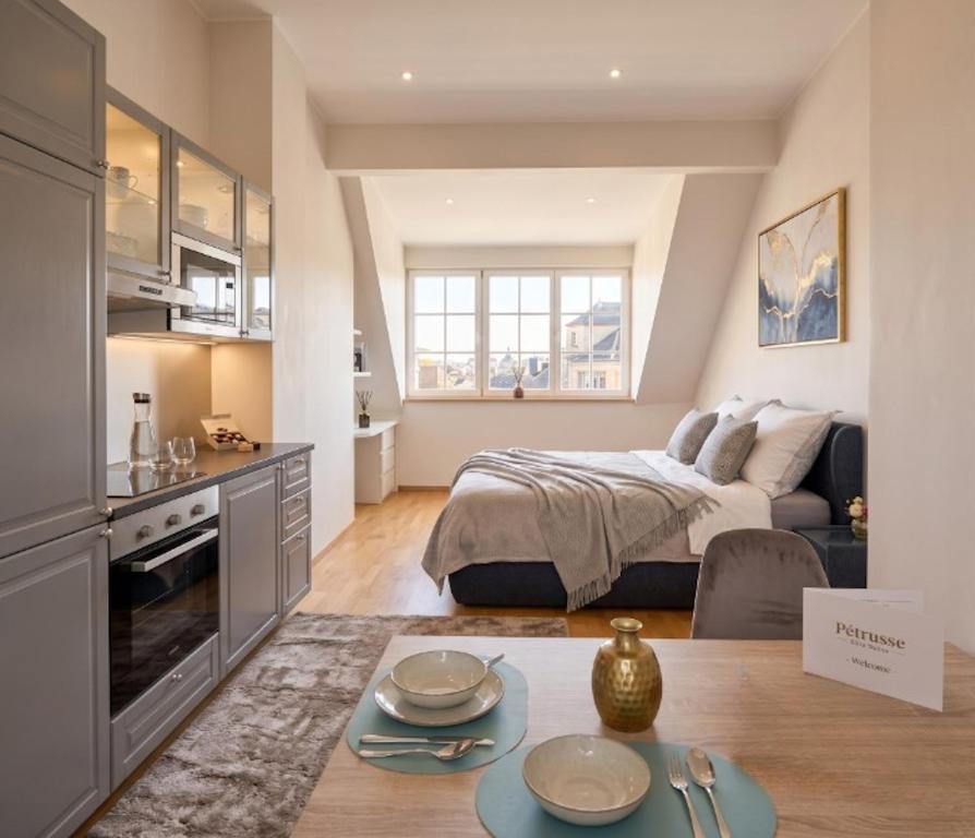 a bedroom with a bed and a table in a room at Pétrusse Élite Suites - Elegant Suites Luxembourg City Center in Luxembourg