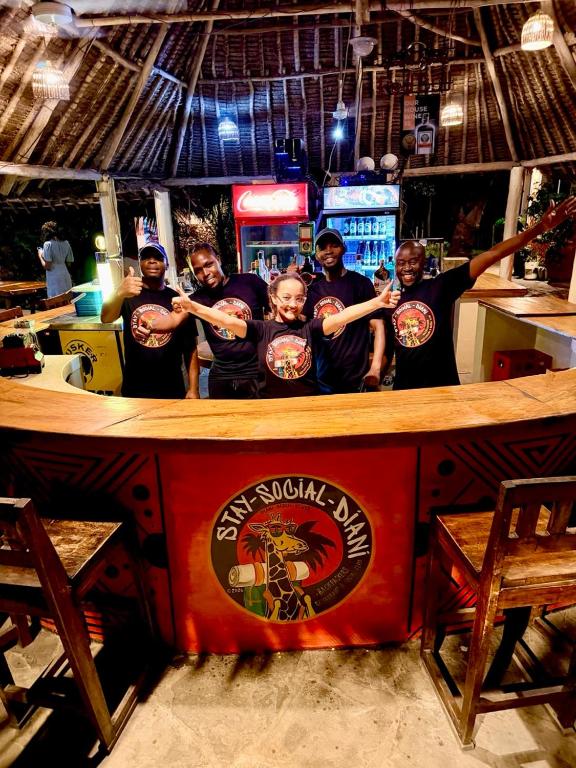 a group of people standing behind a bar at Stay Social Diani - Backpackers & Social Hub in Diani Beach
