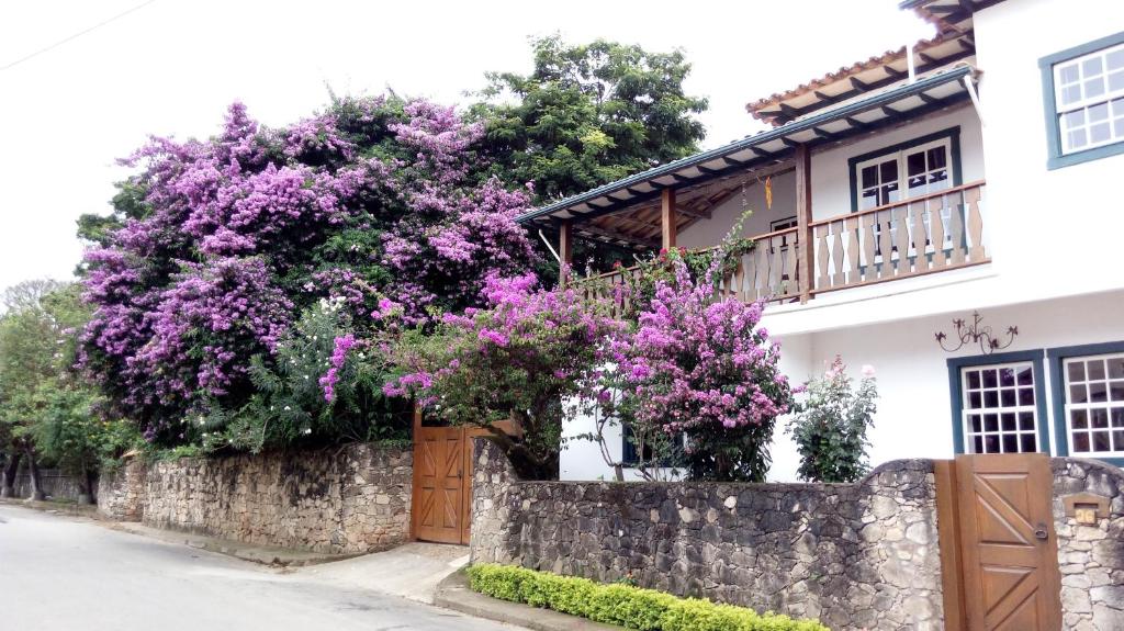 uma casa com flores roxas numa parede em Cama e Café Tiradentes em Tiradentes