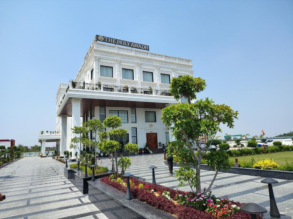 a large white building with flowers in front of it at The Holy Awadh Hotel in Ayodhya