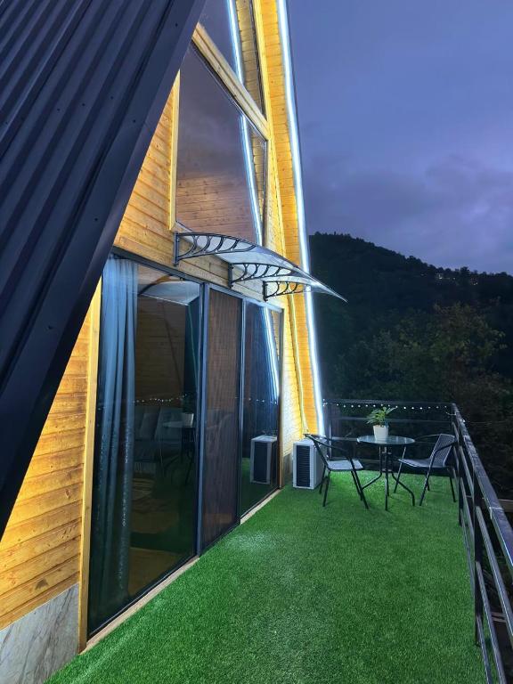 a house with a balcony with a table on the grass at cottages house in Namlisevi