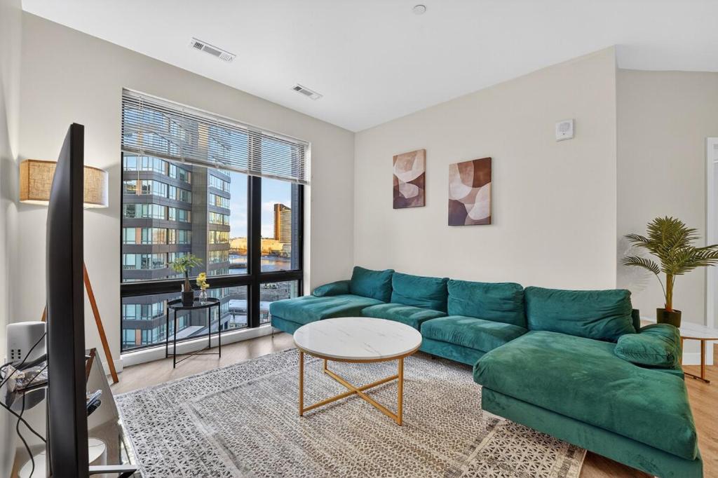 a living room with a green couch and a table at Spacious & Modern 2BR 2BA unit in assembly square in Somerville