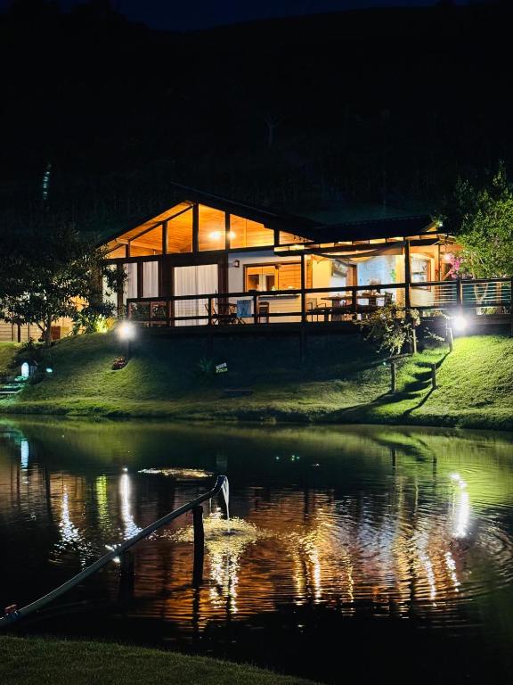 a house on a hill next to a lake at night at Rancho Nosso Lago in Domingos Martins