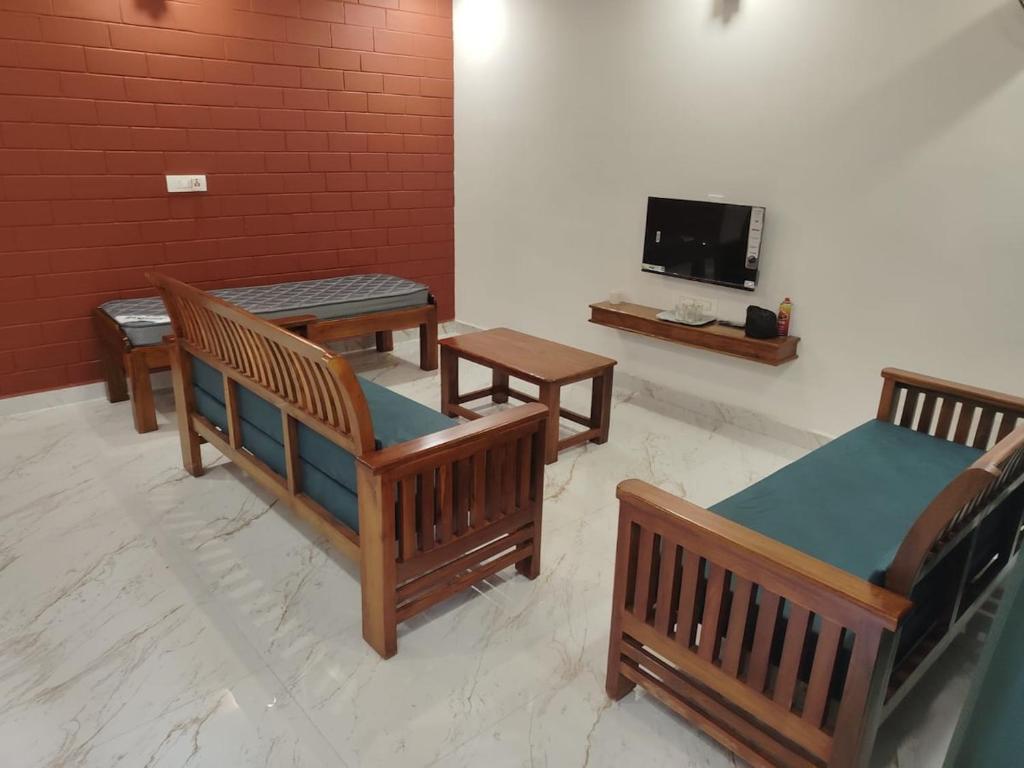 a room with three wooden benches and a tv at Mistora Estate Villa in Suntikoppa