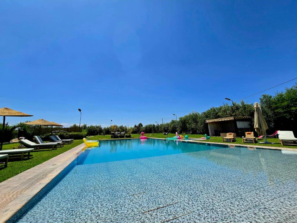 a large swimming pool with chairs and umbrellas at Admylla in Sraghna