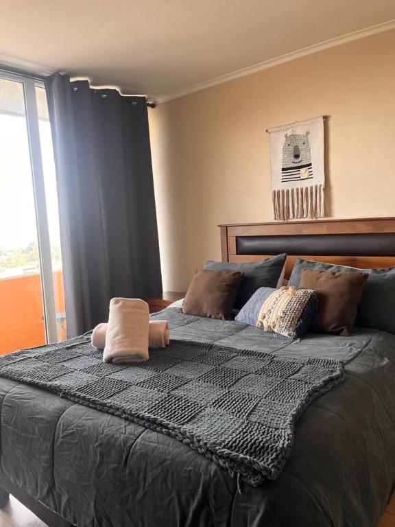 a bedroom with a large black bed with a window at Depto Estudio 1811 Edificio Centro Blanco con estacionamiento in Temuco
