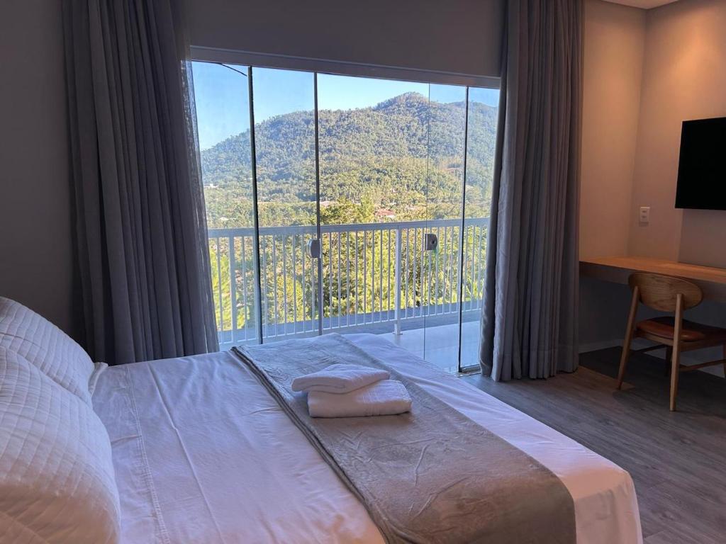 a bedroom with a bed and a large window at Suítes Bela Vista in Pomerode