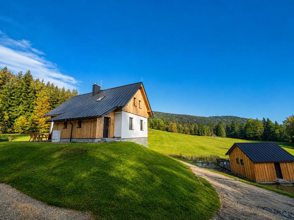 a house on a grassy hill with a barn at Chalupa pod Špičákem in Smržovka