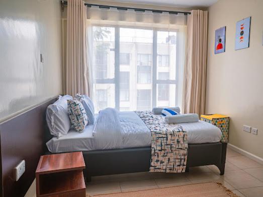 a bedroom with a bed in front of a window at Easy Stay Rongai Poolside 2BR near Karen WiFi and Netflix in Ongata Rongai 