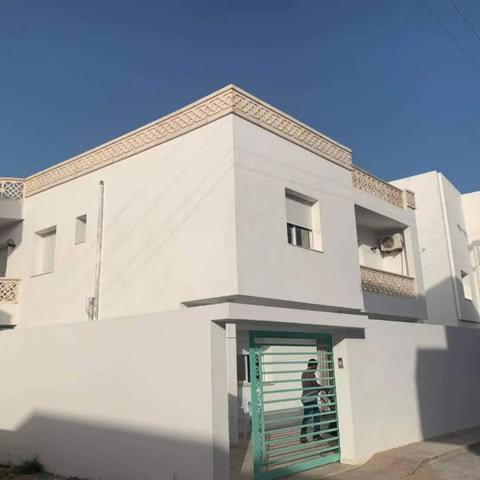 a person walking into a white building with a green door at Dyar Abdellatif in Kelibia