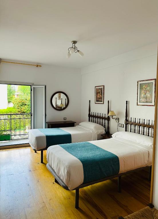 a bedroom with three beds and a balcony at Hostal Pirineos Meliz in Bielsa
