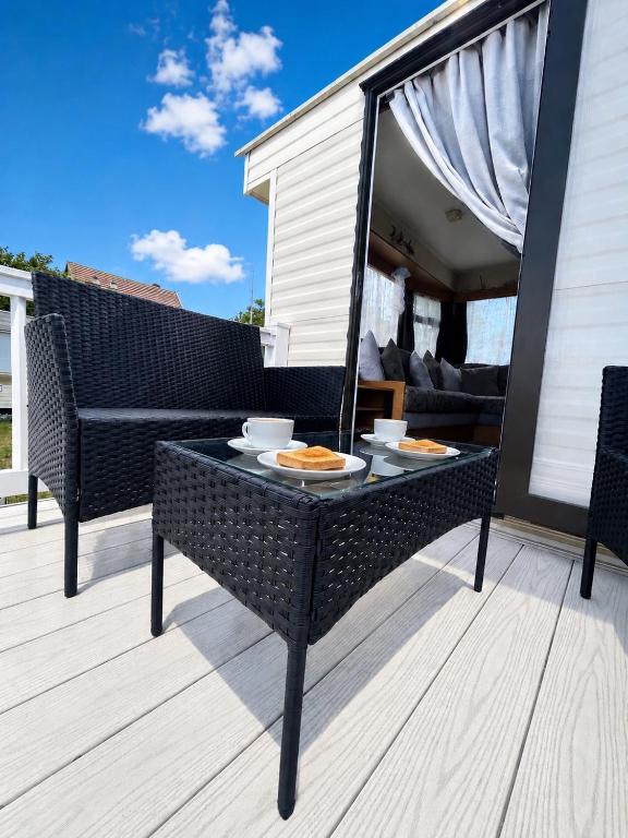 a patio with a table with plates of food on it at The Hemsbee Static caravan 117 Sandsgate Hemsby in Hemsby