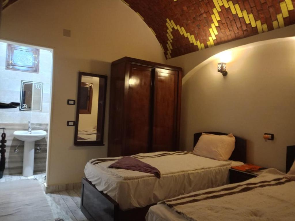 a bedroom with two beds and a sink in it at Manzil Al-Wahati in Bawati