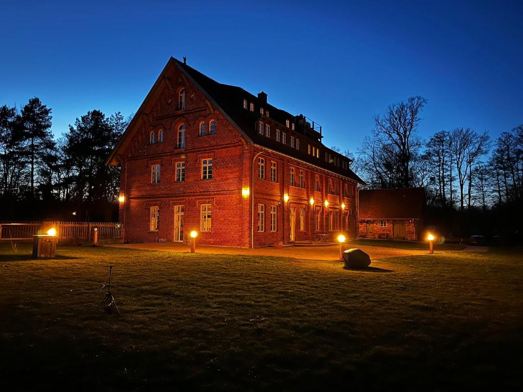 a large brick building with lights in a field at night at Hotel Bolter Mühle - DZ Gerstenkammer in Rechlin