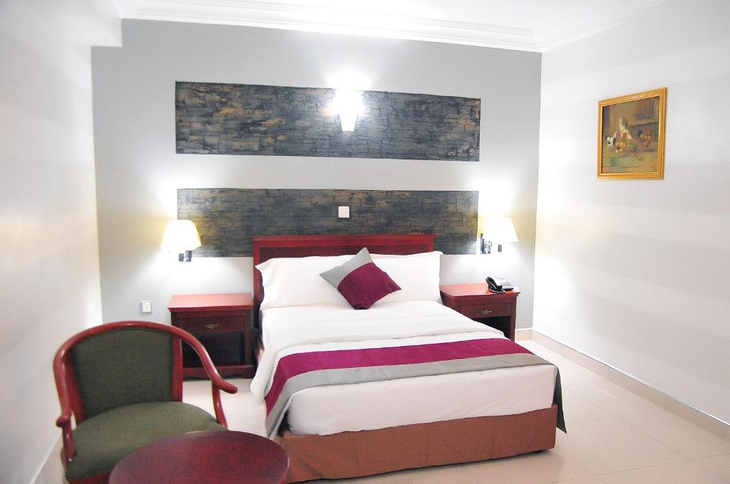 um quarto de hotel com uma cama e uma cadeira em Tomreik Hotel em Acra
