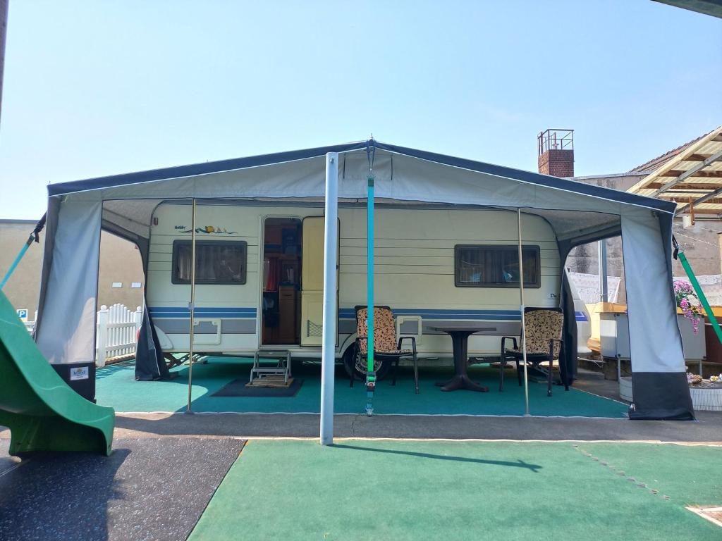 a camper tent with a table and chairs under it at Ferienwohnwagen Rudolf in Coswig