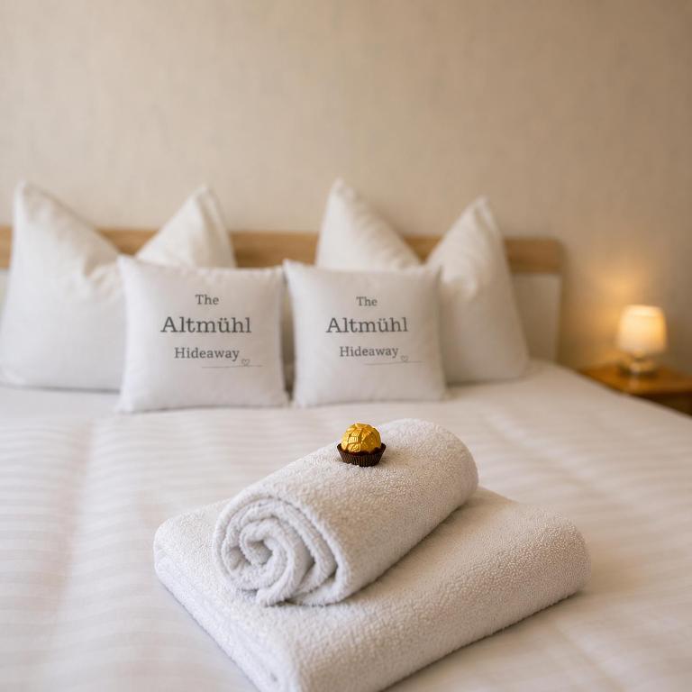 a white bed with a towel on it with pillows at Altmühl Hideaway Apartment 1 in Treuchtlingen