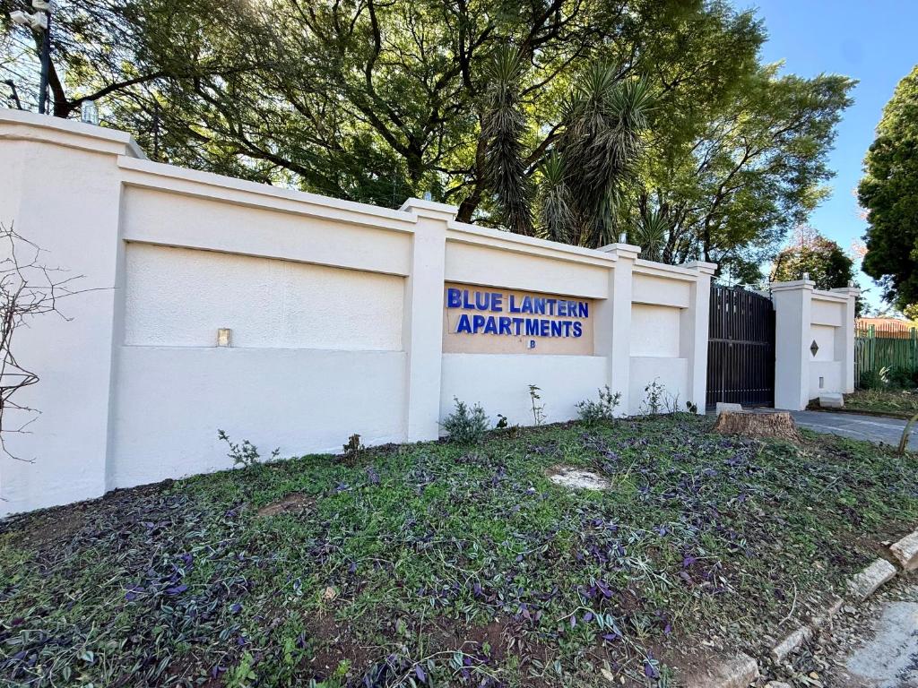 a white building with a sign that reads blue lantern apartments at Blue Lantern Bed and Breakfast in Kempton Park