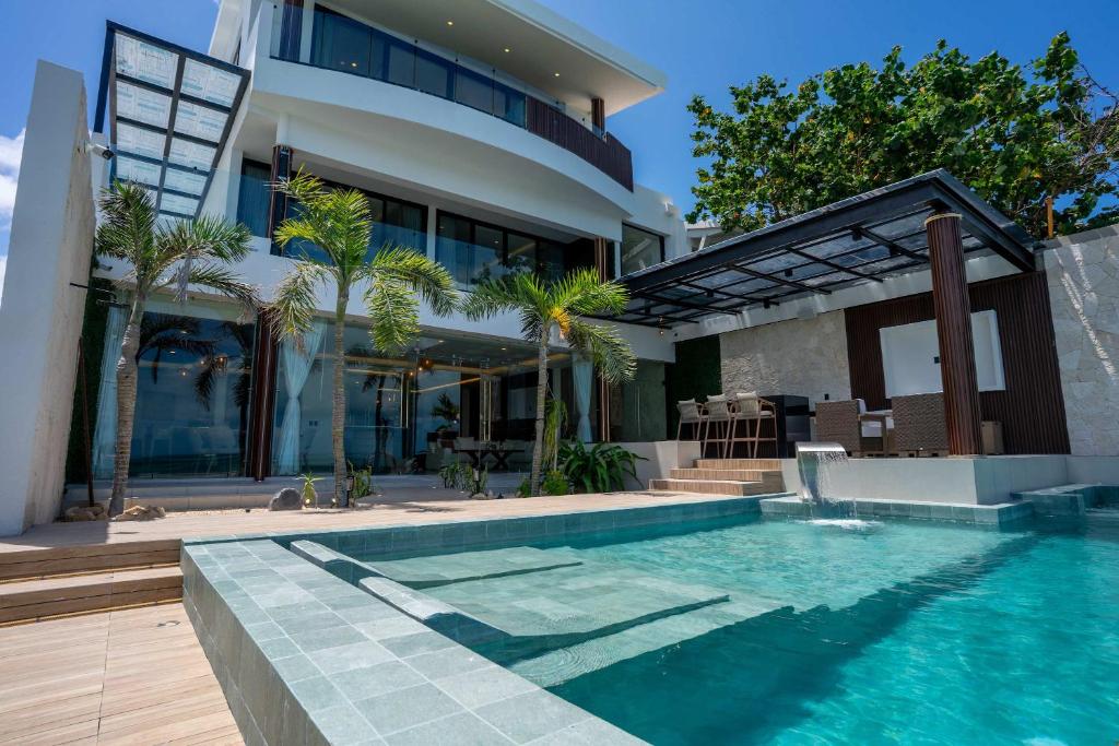a house with a swimming pool in front of a house at Villa Magdalena - 7BR - Oceanfront with Heated Pool in Cancún