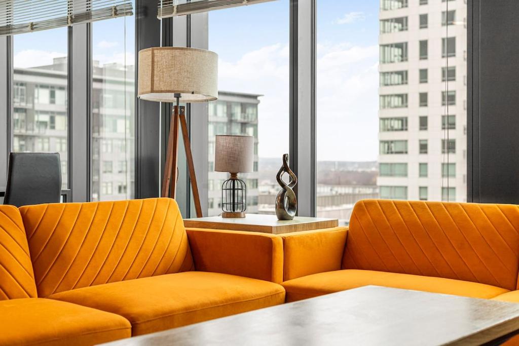 a living room with two orange couches and a table at High-end Modern 3BR 3BA Condo Assembly Square in Somerville