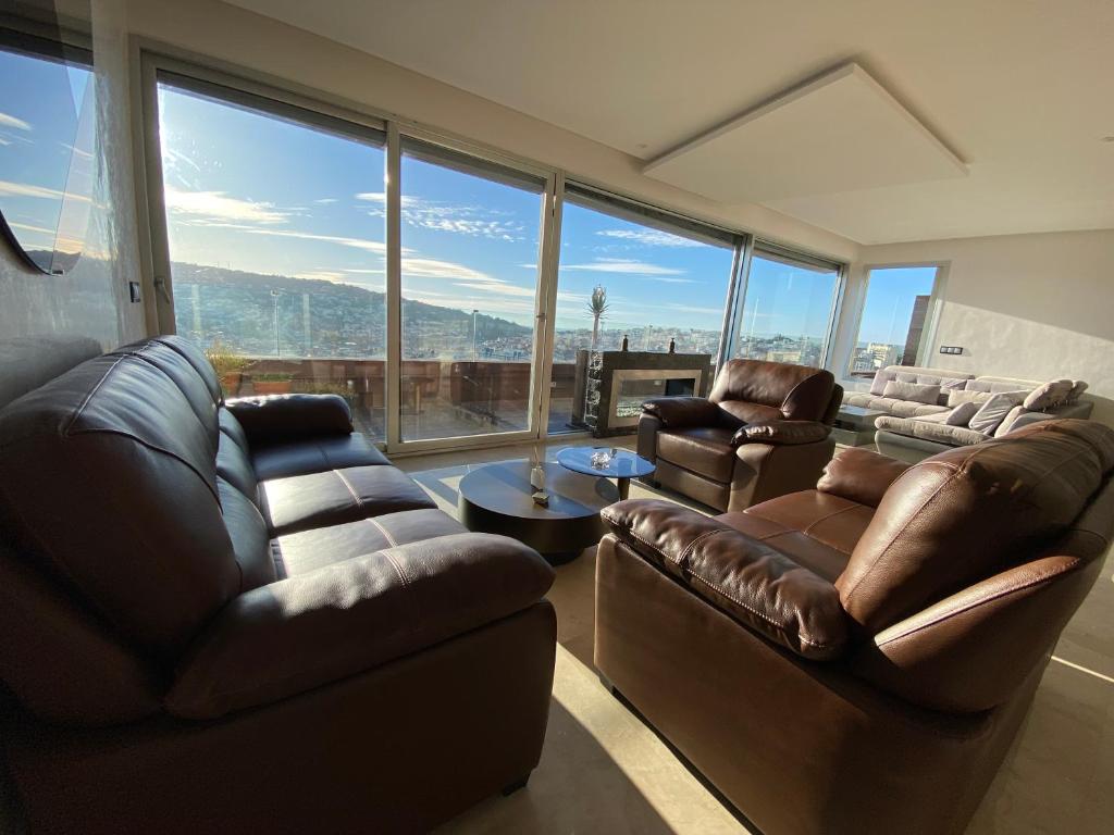 a living room with leather furniture and large windows at Apartment in Tangier