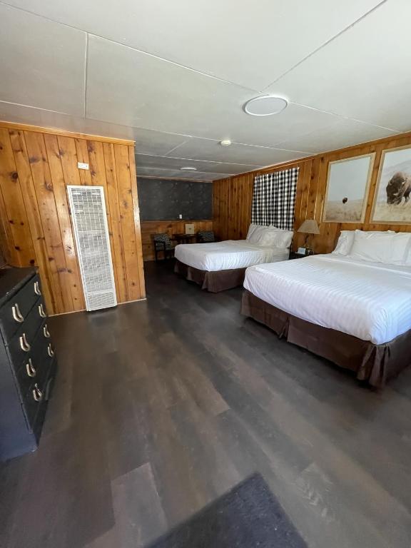 two beds in a room with wooden walls at The Spruce Lodge in South Fork