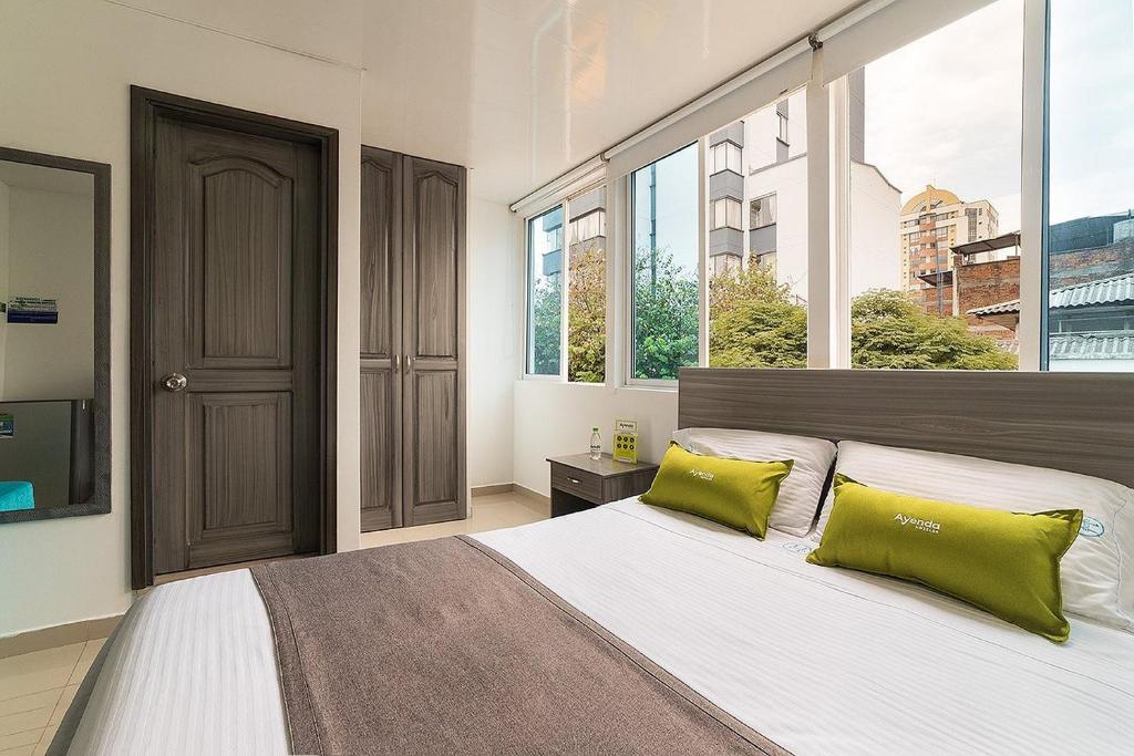 a bedroom with a large bed with two green pillows at Hotel Exito La 21 in Pereira