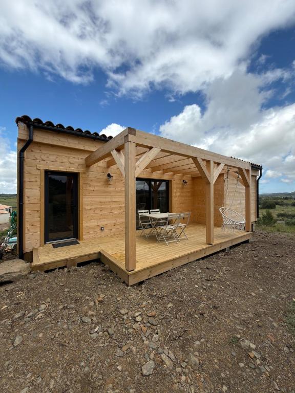 a cabin with a deck with a table and chairs at Chalet de Saint Martin in Roquefort-des-Corbières