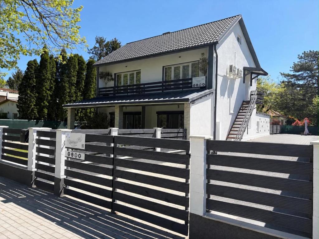 a white house behind a fence with a gate at Fifteenapartman in Balatonföldvár
