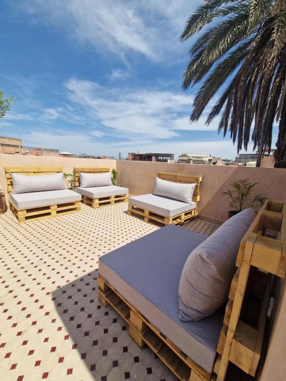 a patio with two beds and two chairs and a palm tree at Riad Dar Yamna Marrakech in Marrakesh