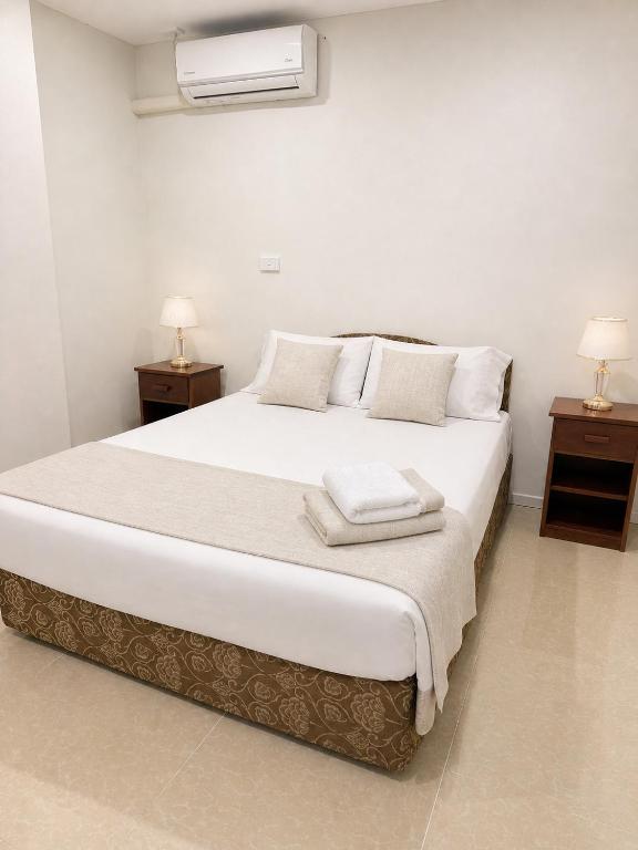 a bedroom with a large white bed with two night stands at Trendy Edge Apartments in Nadi