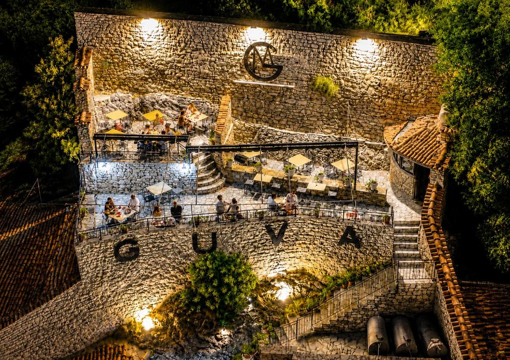 a group of people on a balcony at night at Guva Mangalem Boutique Hotel & Restaurant -Berat Old Town View in Berat