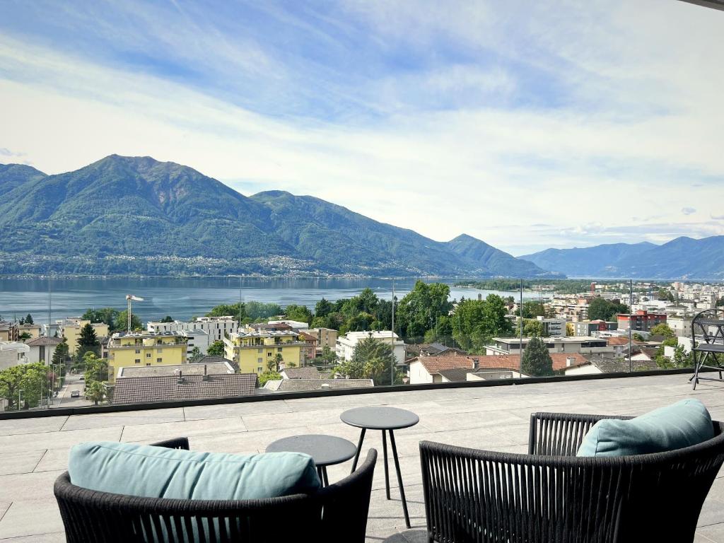 a balcony with two chairs and a view of a city at Luxury Lake View Apartment Minusio by HolAp in Minusio