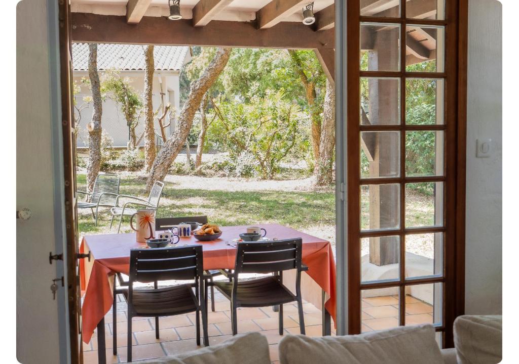 a table and chairs on a patio with a view of a yard at Maison de Charme,Plage et Forêt, 6 personnes in Seignosse