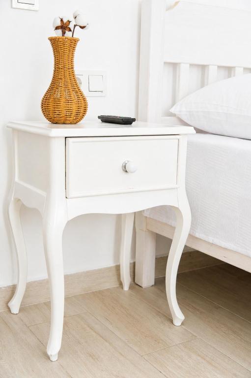 a white table with a vase on it next to a bed at Hayal Ada in Bozcaada