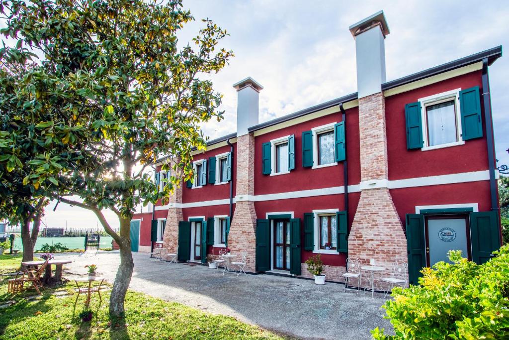 a red building with blue windows and a tree at Ca'trecamini in Ca Dolfin