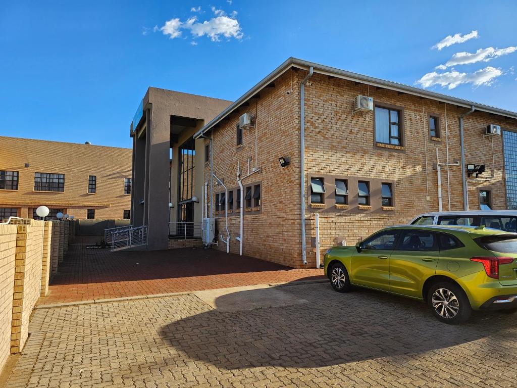 a green car parked in front of a brick building at TACOA Boutique Hotel in Westonaria