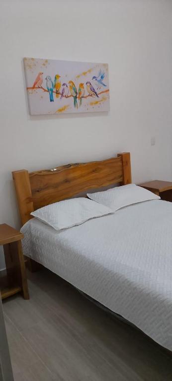 a bedroom with a bed with a picture on the wall at Hostería santa María in Filandia