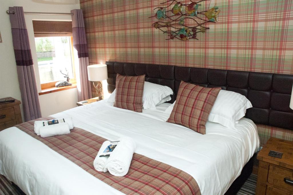 a bedroom with a large bed with towels on it at Strathspey Cottage in Carrbridge