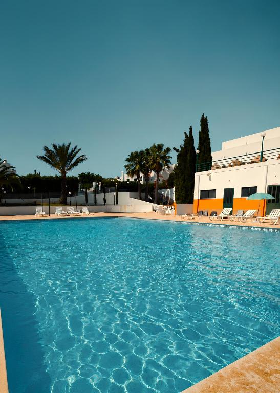 a blue swimming pool with chairs and a building at Rialgarve in Faro