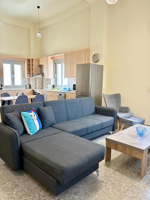 a living room with a blue couch and a kitchen at Nóstos Home in Kos